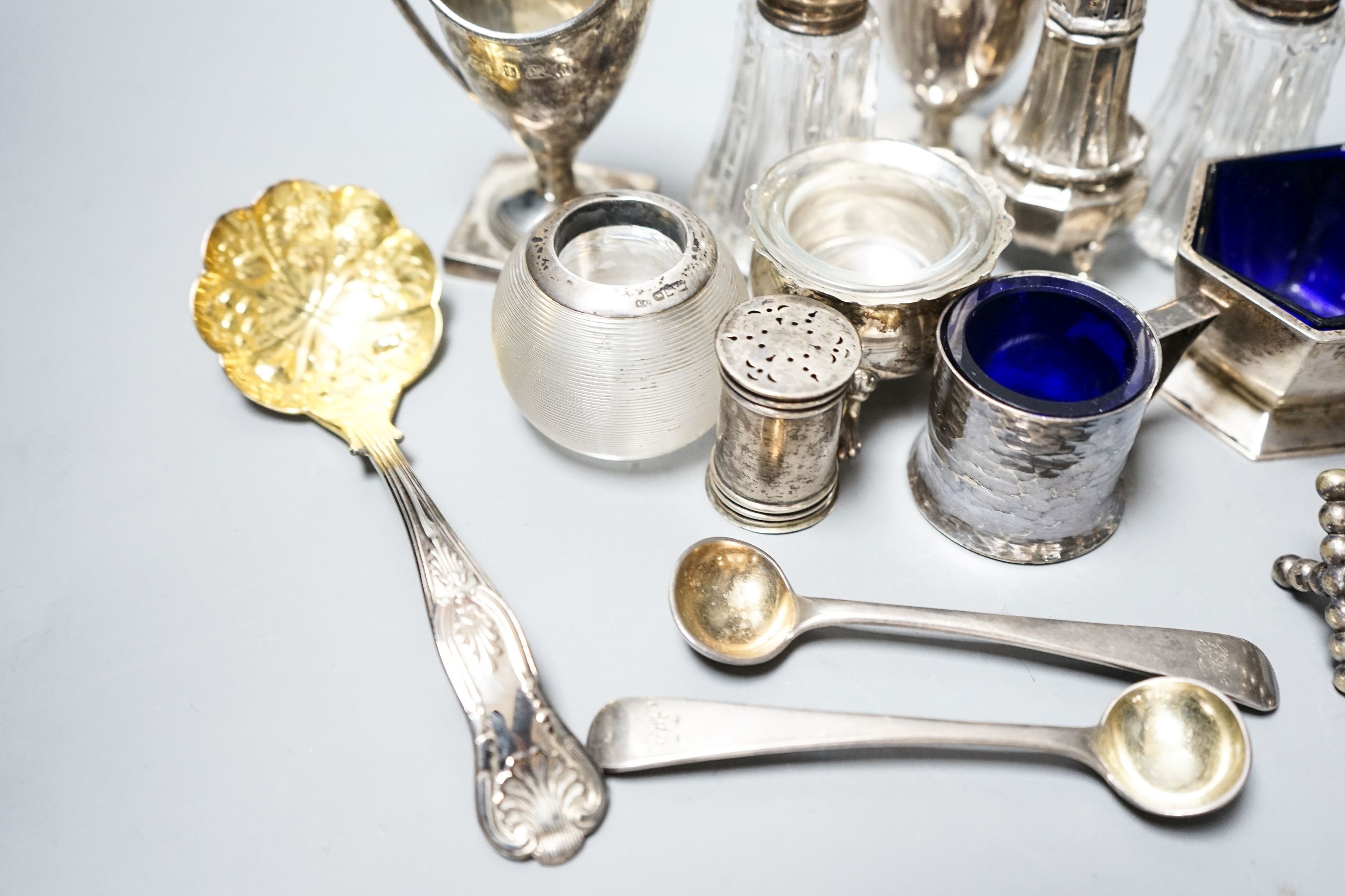 A group of small silver including condiments, match strike, cream jug, plated knife rests etc.